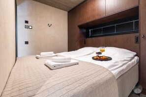 A neatly made bed with a white duvet, a tray of fruit and a glass of orange juice, and a set of folded towels. - North Suite Sky by Holiday in Lapland (Levi)