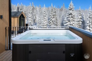 A hot tub on a wooden deck with a view of snow-covered trees. - North Suite Sky by Holiday in Lapland (Levi)