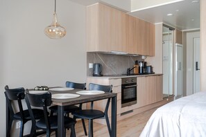 A modern kitchen with a dining area, wooden cabinets, a built-in oven, and a hanging light fixture. - Äkäsentie 1 A 202 by Holiday in Lapland (Äkäslompolo)