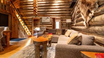 L’intérieur d’une cabane en rondins, avec un escalier en bois, un ensemble de canapés et un décor de style rustique.