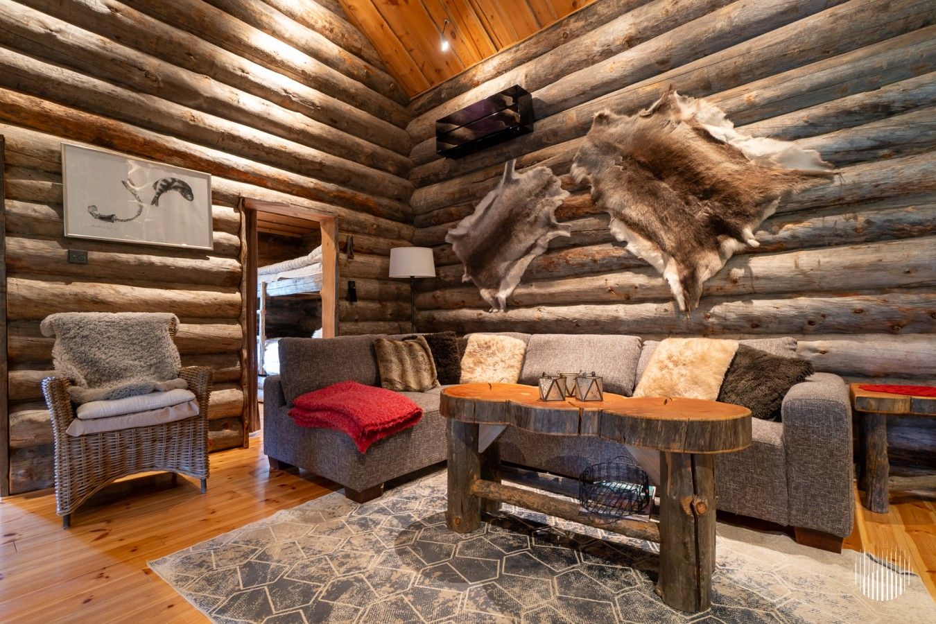 A log cabin interior with a sofa, a chair, a table, and a rug.
