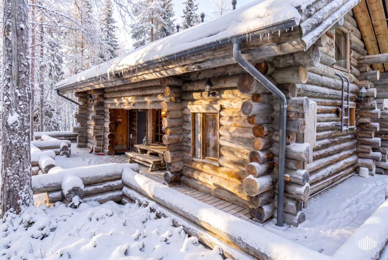 Une cabane en rondins avec une façade en bois, un porche et une cheminée.