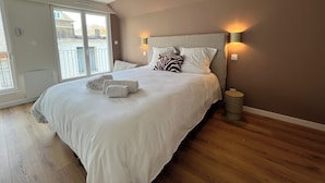 Un dormitorio con una cama grande, una lámpara de techo, una lámpara de noche y vistas a través de una puerta corrediza.