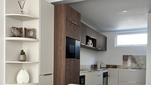 Una cocina moderna con armarios blancos, horno empotrado y ventana sobre el fregadero.