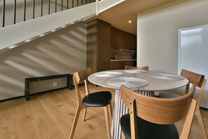 A dining area with a round table, wooden chairs, and a staircase in the background. - Metsonlinna 204 by Holiday in Lapland (Levi)