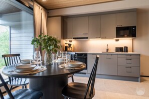 Een moderne keuken met een eethoek, gedekt voor een maaltijd, met een ronde tafel, stoelen en een vaas met bloemen.