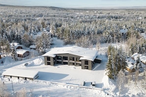 Ein modernes Gebäude mit flachem Dach, umgeben von einem verschneiten Wald.