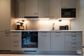 Una cocina moderna con horno Bosch, cafetera y microondas.