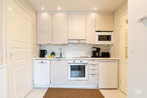A compact kitchen with white cabinetry, a microwave, a coffee maker, and a dishwasher. - Cozy and peaceful apartment in Äkäslompolo (Äkäslompolo)