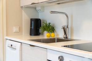 Eine moderne Küche mit einer Edelstahl-Spüle, einer schwarzen Kaffeemaschine und einem Blumentopf mit Zitronen.