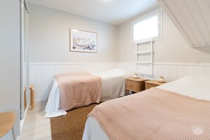 Ein Schlafzimmer mit zwei Betten, einem Fenster, einer Heizung und einem gerahmten Bild an der Wand.