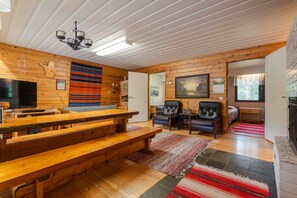L’intérieur d’un chalet chaleureux, avec un banc en bois, une cheminée et un coin repas.