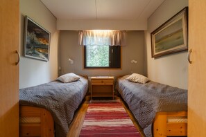 A compact room with two single beds, a desk, and a window with a view of greenery.