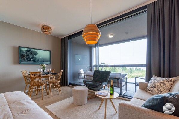 A modern living room with a dining area, large windows, and a balcony.