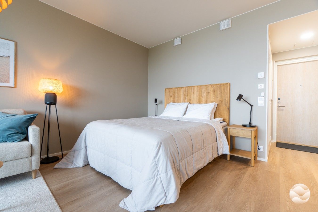 Un dormitorio con cama, mesita de noche, lámpara y una puerta.