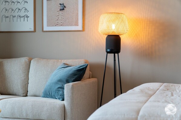 A room with a sofa, a standing floor lamp, and a bed.