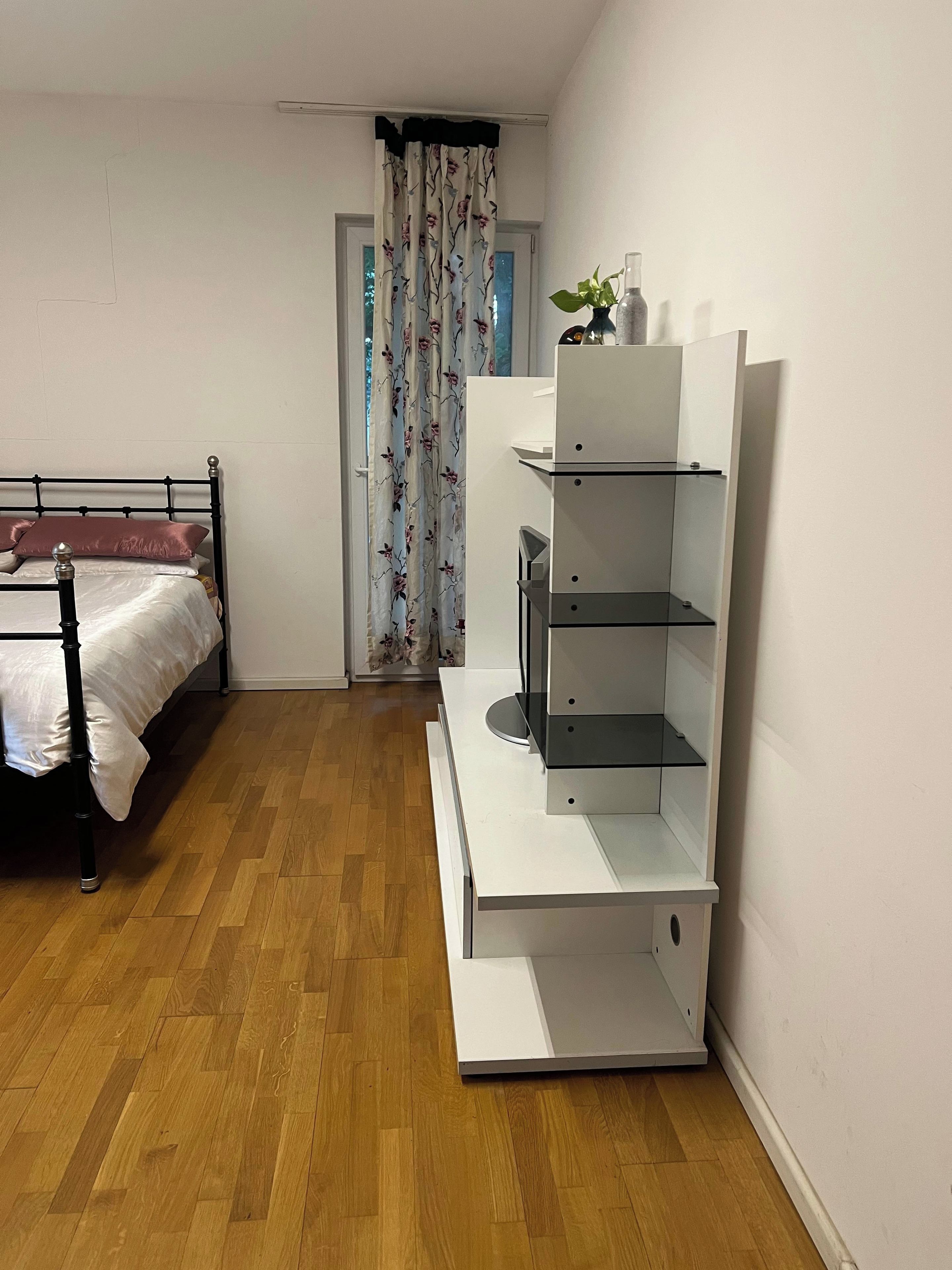Ein Schlafzimmer mit einem Bett, einem weißen Nachttisch, einem weißen Kleiderschrank und einem Holzboden.