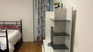 Une chambre à coucher avec un lit, une table de chevet blanche, une armoire blanche et un plancher en bois.