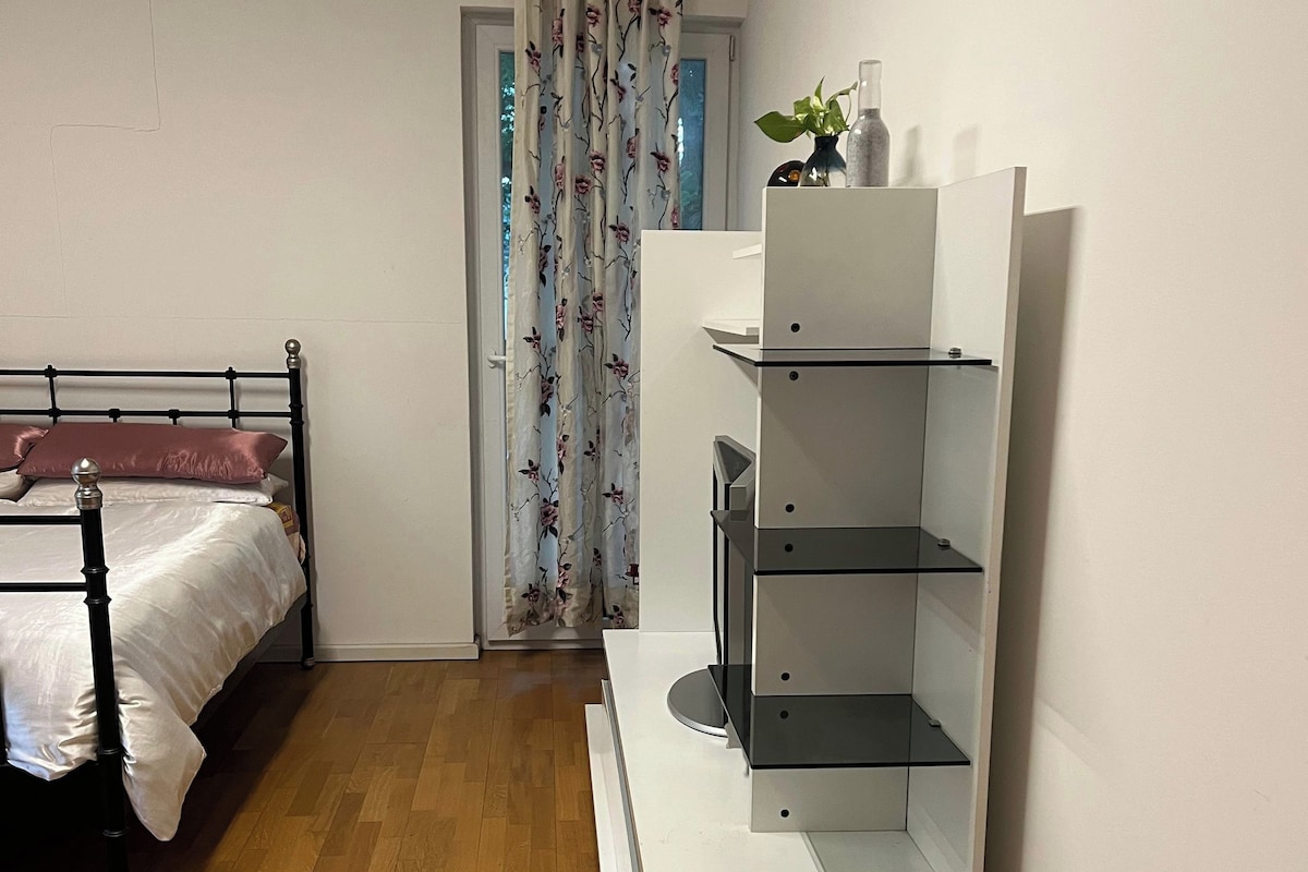 Une chambre à coucher avec un lit, une table de chevet blanche, une armoire blanche et un plancher en bois.