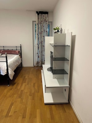 Ein Schlafzimmer mit einem Bett, einem weißen Nachttisch, einem weißen Kleiderschrank und einem Holzboden.