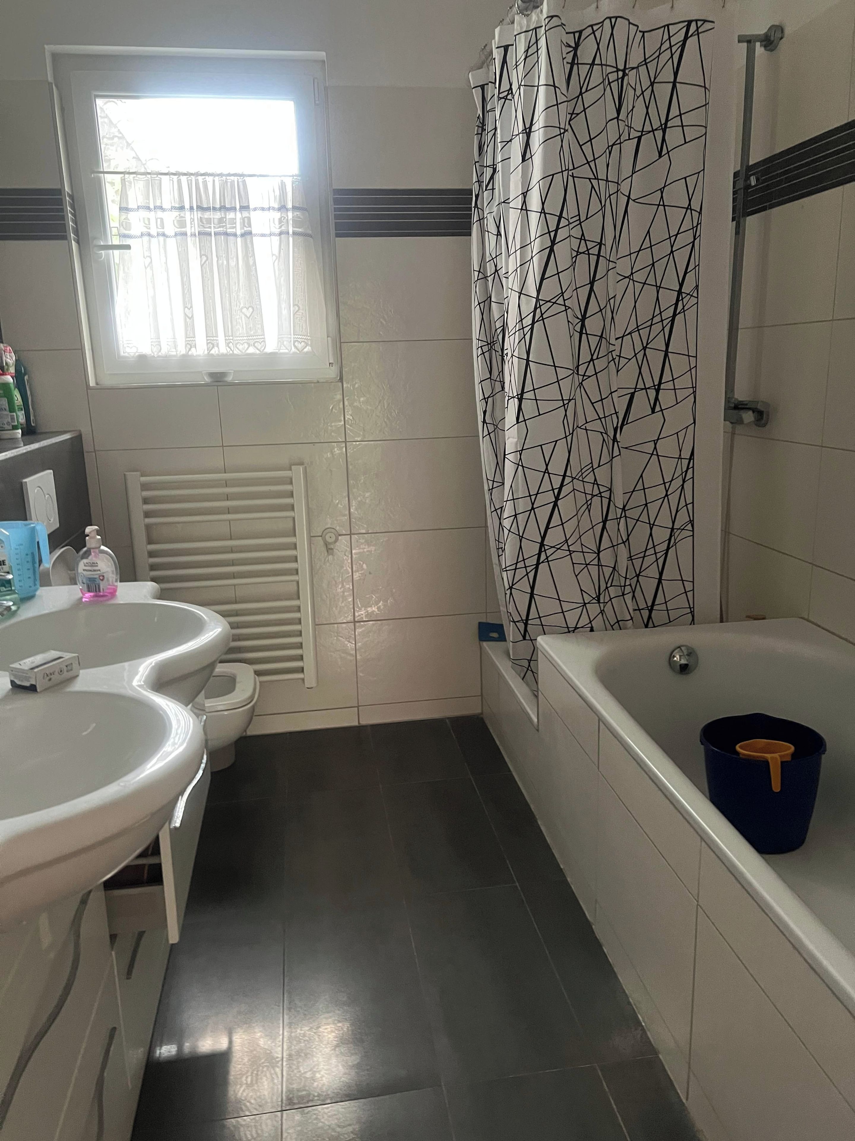 Ein Badezimmer mit Toilette, zwei Waschbecken, einer Badewanne und einer Duschvorhang.
