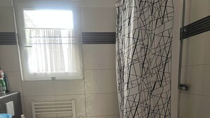 Une salle de bain comprenant des toilettes, deux lavabos, une baignoire et un rideau de douche.