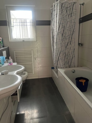 Ein Badezimmer mit Toilette, zwei Waschbecken, einer Badewanne und einer Duschvorhang.