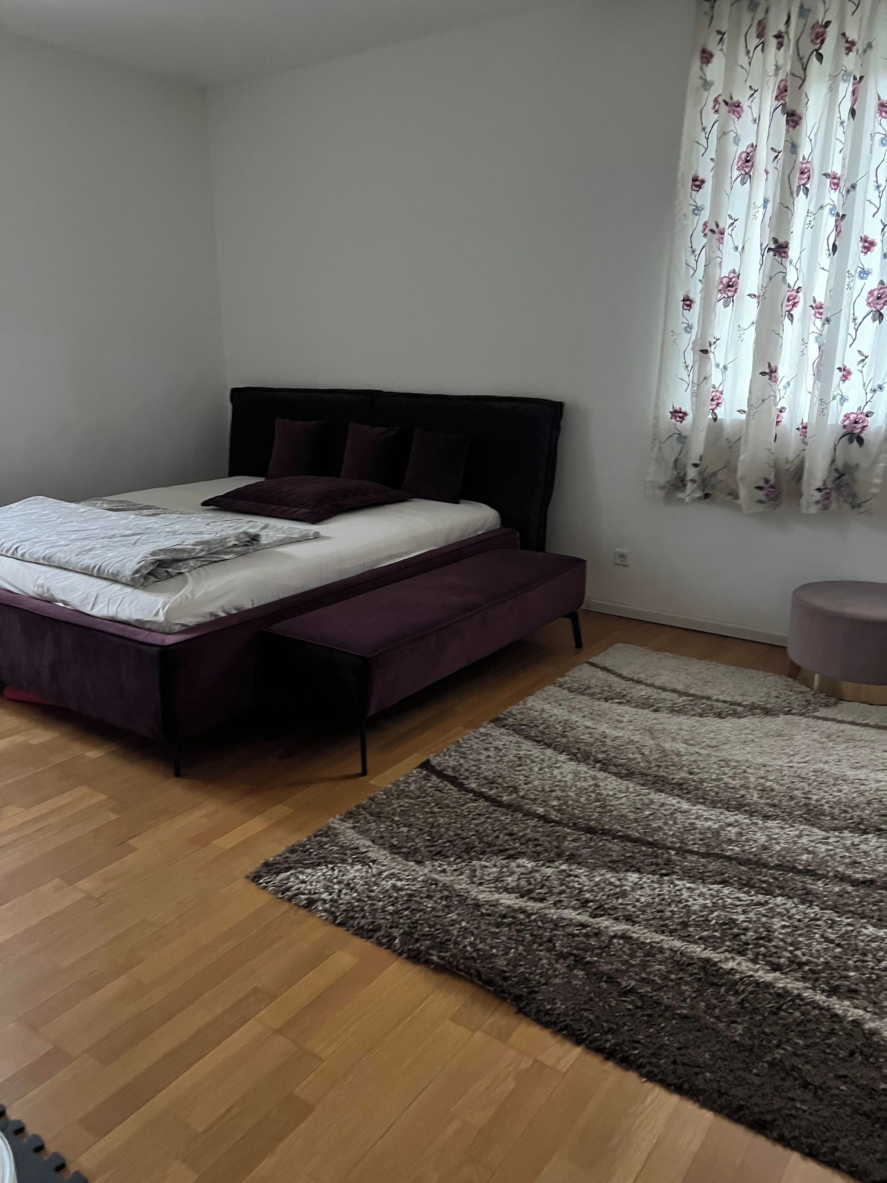 Ein Schlafzimmer mit Bett, Teppich und einem Fenster mit Vorhängen.
