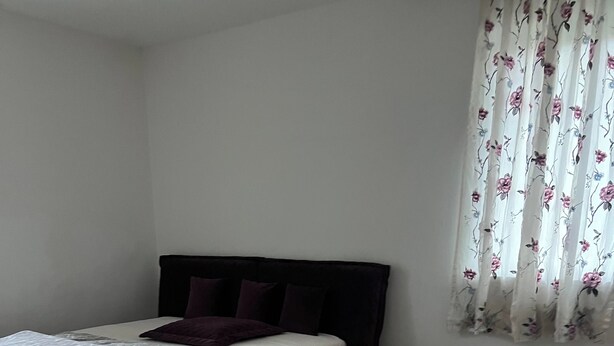 Une chambre à coucher avec un lit, un tapis et une fenêtre avec des rideaux.