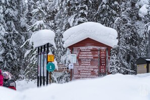 Lumipeitteinen opastekyltti, jossa on useiden yritysten nimiä ja niiden aukioloajat.