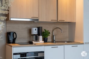 A modern kitchen with wooden cabinets, a coffee maker, a sink, and a dishwasher.