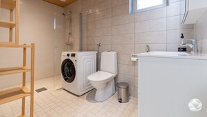 Casa de banho moderna com máquina de lavar, sanita e lavatório.