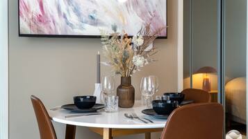 A dining table set with black bowls, wine glasses, and a vase with dried flowers.