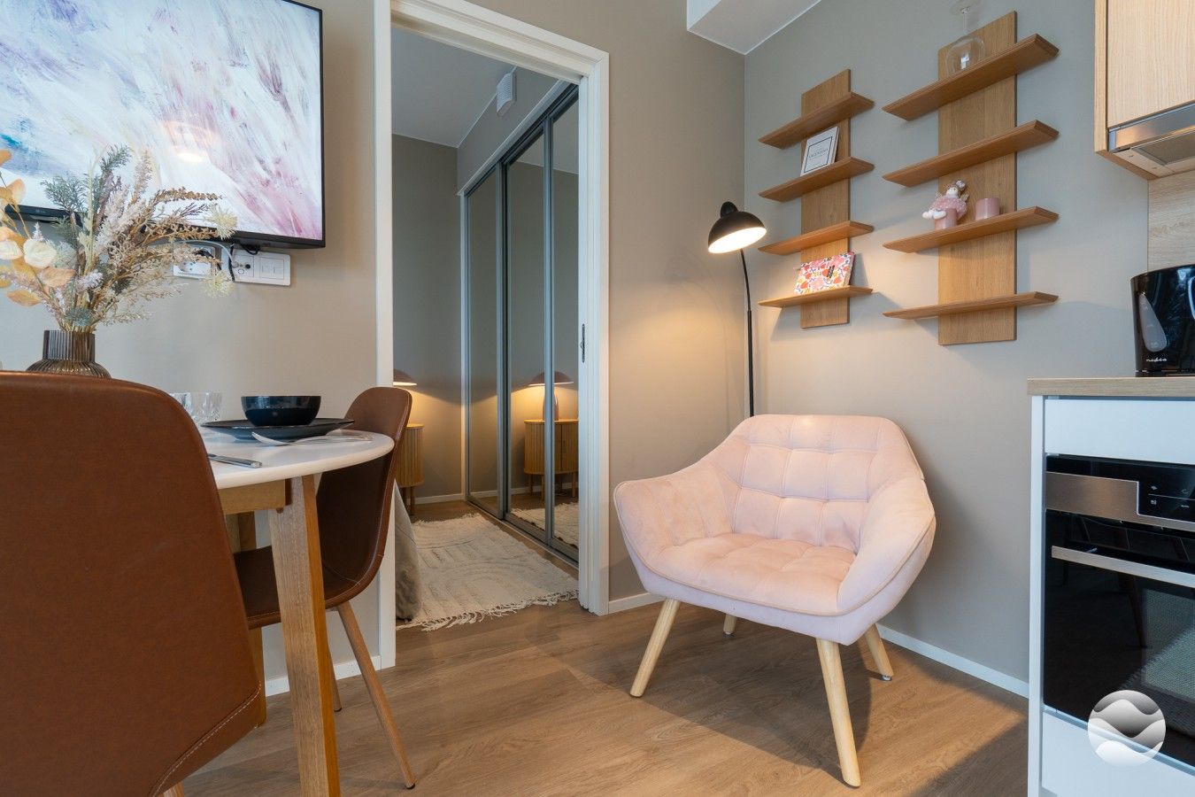 Una cocina moderna con estantes de madera, un comedor con mesa y sillas, y una gran obra de arte en la pared.