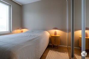 A bedroom with a bed, two bedside tables with lamps, a window, and a door. - Marinan Portin Kapteeni A34 by Holiday in Kalajoki (Kalajoki)