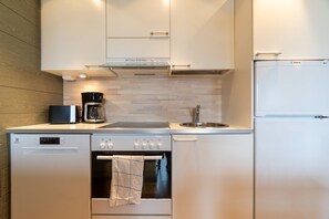 A compact kitchen with a Bosch refrigerator, a coffee maker, and a dishwasher.