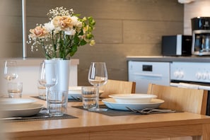 A dining table set with plates, glasses, and a vase with flowers.