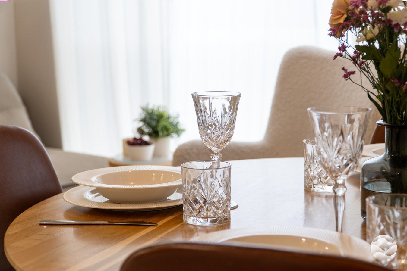 Una mesa de comedor dispuesta con platos, vasos y cubiertos.