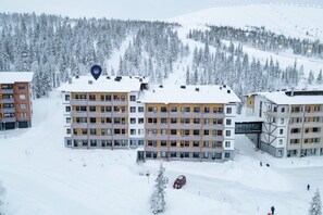 A multi-story hotel with a snow-covered roof, surrounded by a forested area.