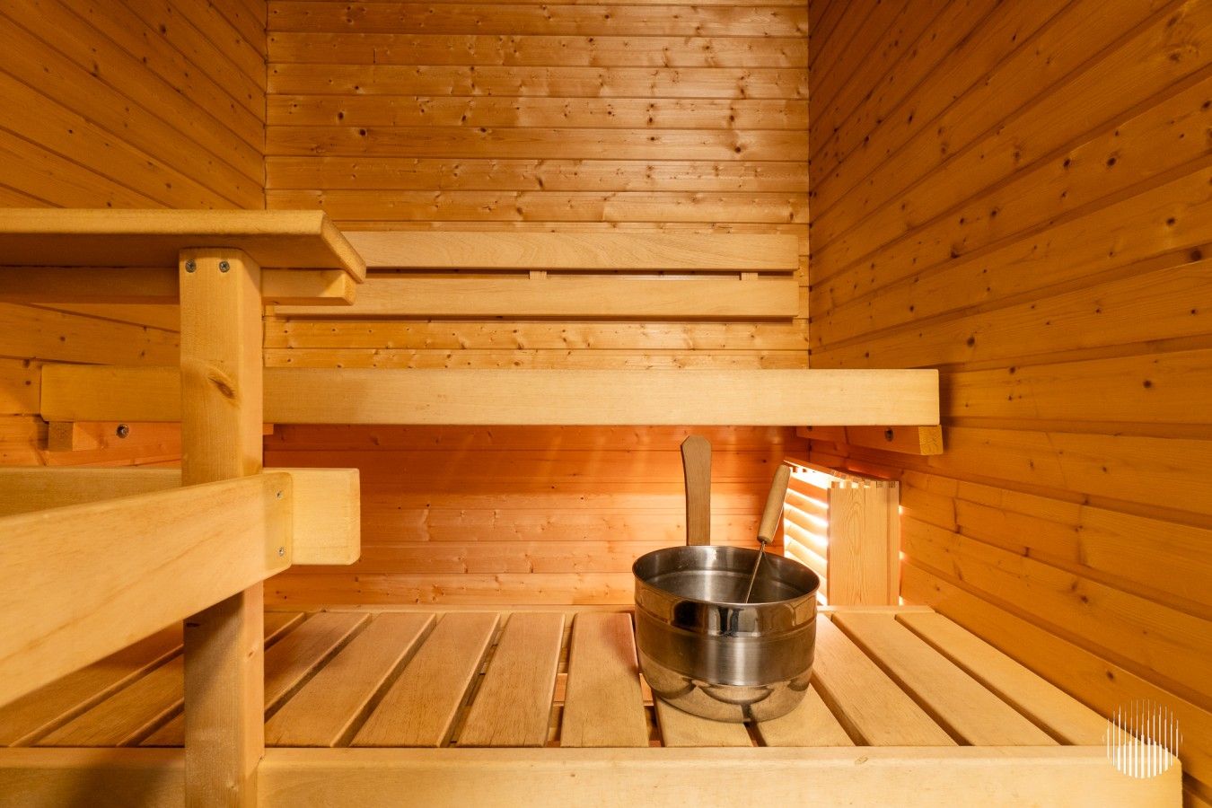 Una sauna con panche in legno e una vasca in metallo.