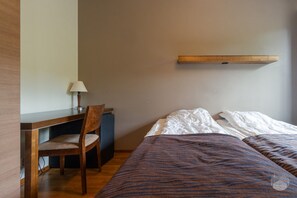 A hotel room with a desk, chair, and a bed with a striped bedspread.