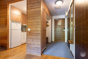 A compact kitchen with a refrigerator, cabinets, and a wooden wall.