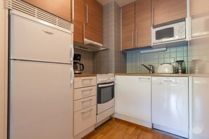 Cuina compacta amb nevera, forn, microones i rentaplats.