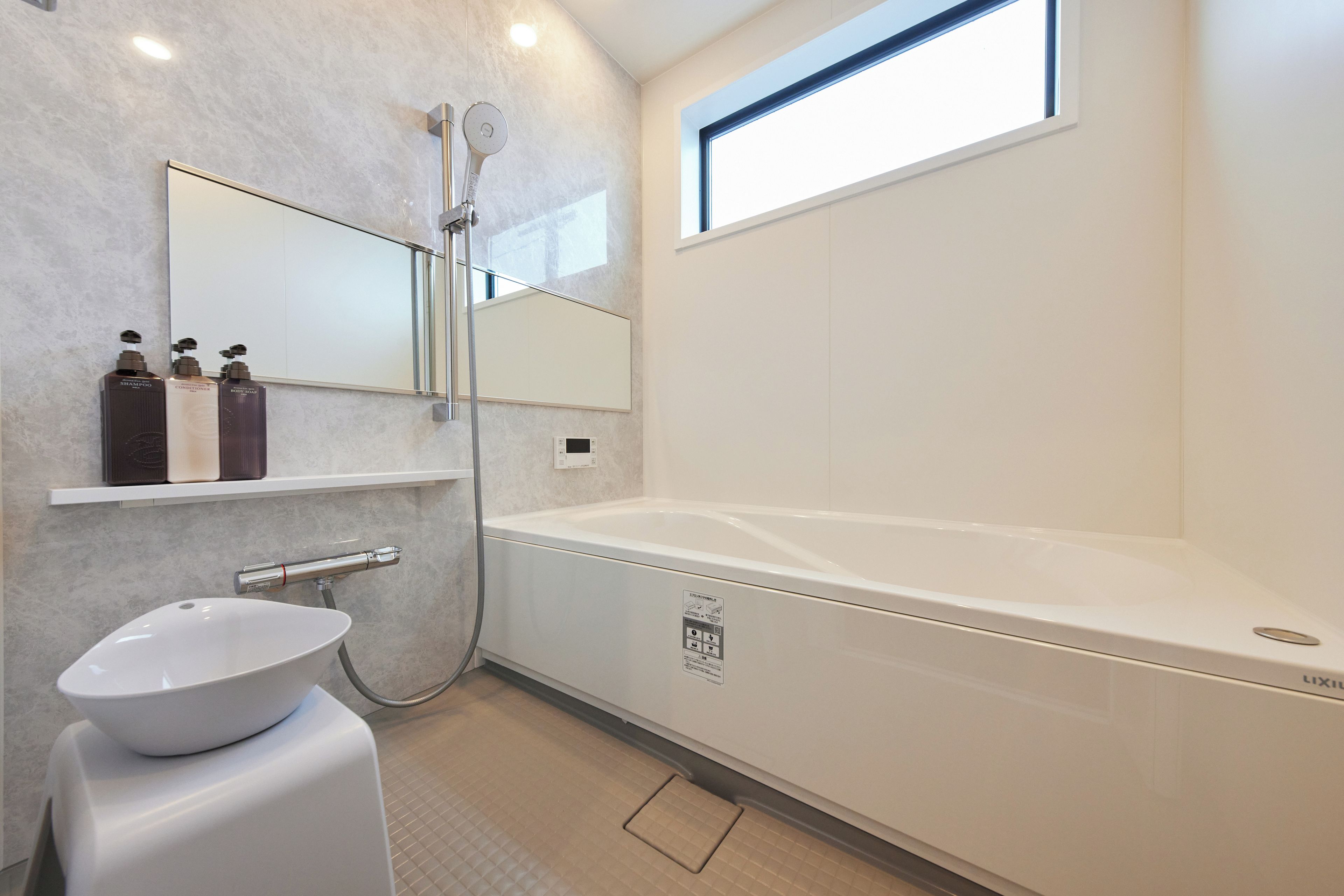 A modern bathroom with a bathtub, a sink, and a shower. There is a mirror above the sink and a window above the bathtub.