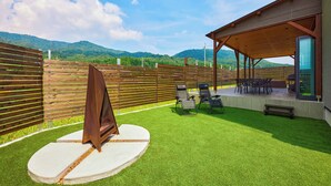A patio area with artificial grass, a barbecue grill, and outdoor seating.