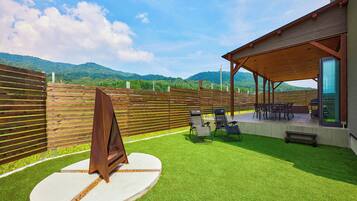 A patio area with artificial grass, a barbecue grill, and outdoor seating.