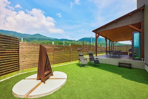 A patio area with artificial grass, a barbecue grill, and outdoor seating.