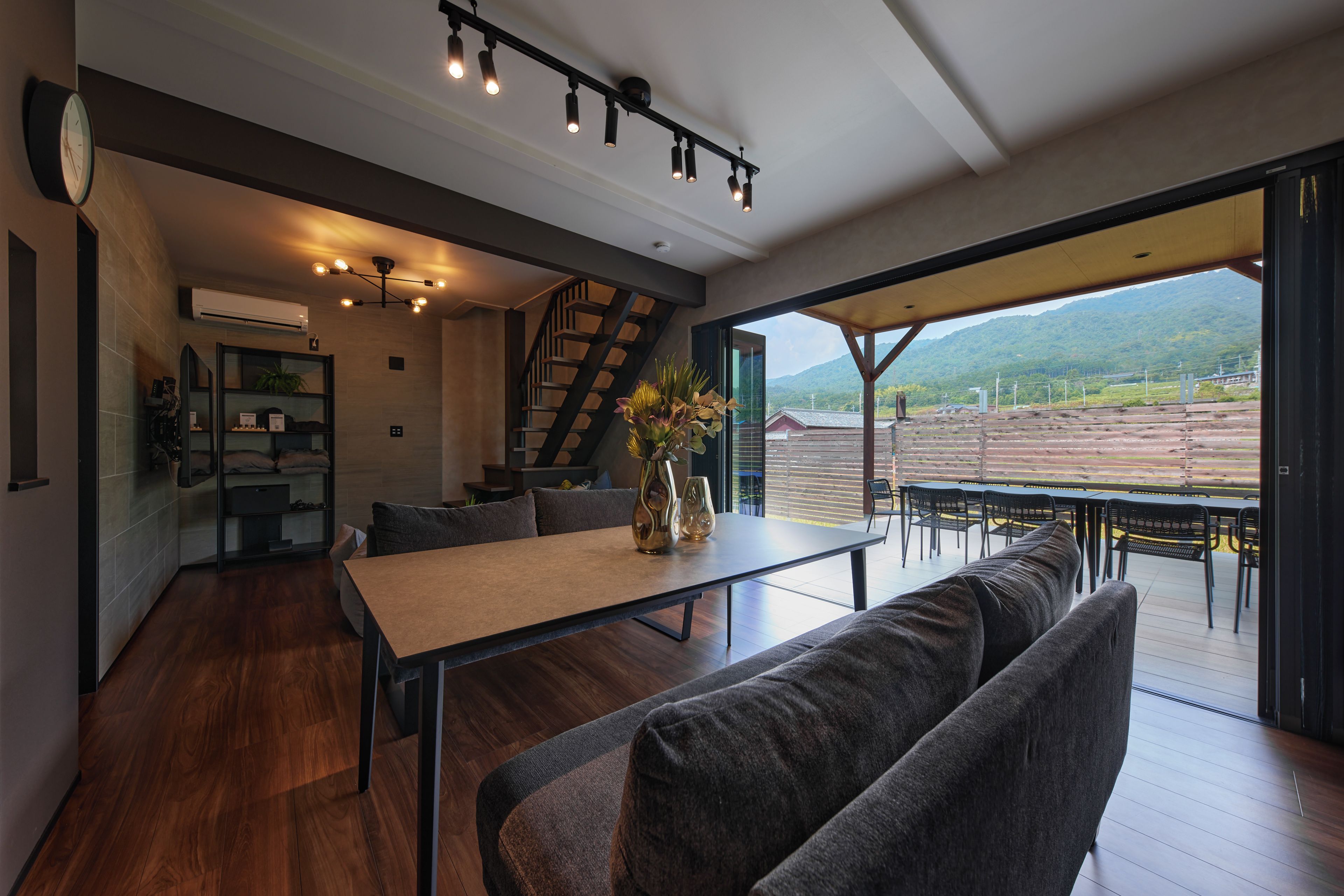 Un intérieur moderne comprenant un coin repas, un escalier et une vue sur un paysage montagneux.