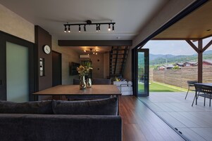 A modern interior with a dining area, sofa, and a view of a residential area.