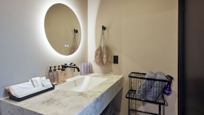 A bathroom with a marble sink, a round mirror, and a towel rack.
